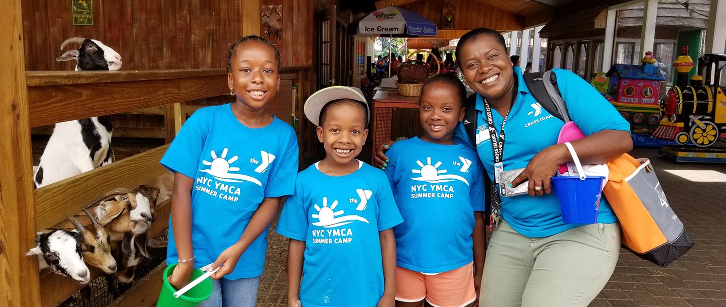 Three kids and a YMCA staff member at a YMCA summer day camp.