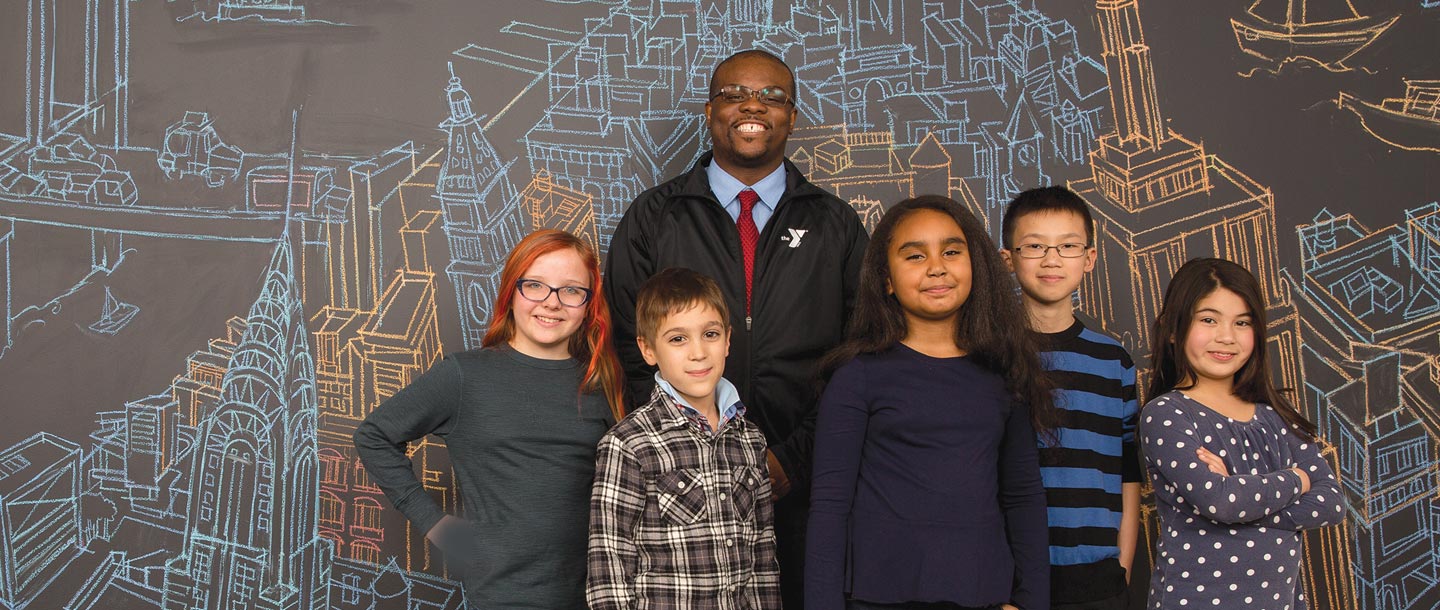 A group of kids and a Y staff member standing in front of a map of NYC.