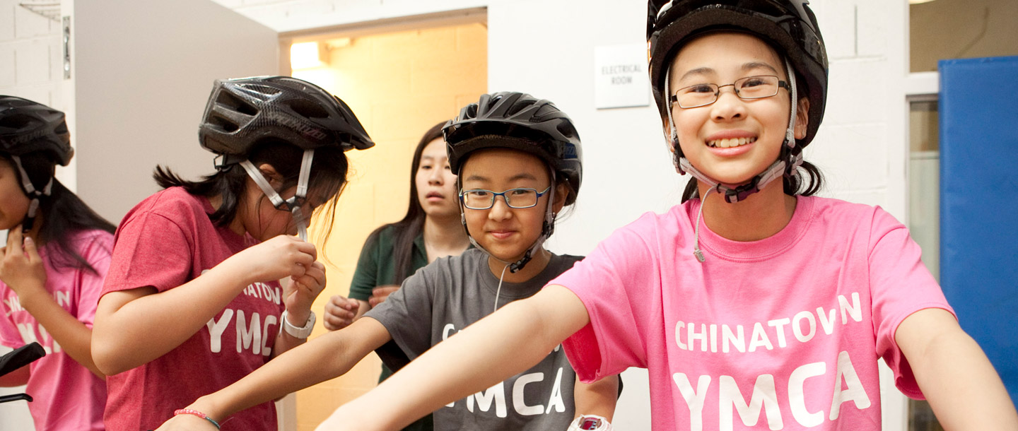 Girls with bike helmets wearing Chinatown YMCA tee shirts.