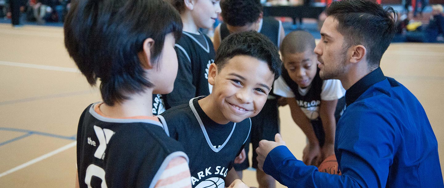 Boy with basketball smiling at Park Slope Armory YMCA in Brooklyn