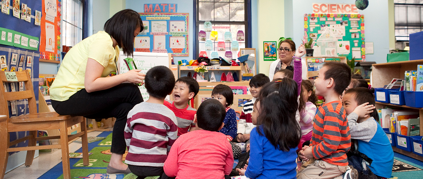 Teacher reading story to preschoolers sitting on classroom floor at YMCA UPK class in Queens