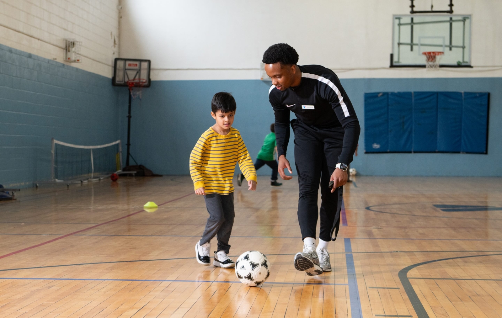 coach and kid with soccer ball in gym