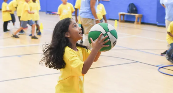 A young girl plays basketball in the Jamaica YMCA gymnasium.