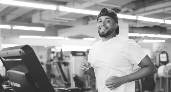 guy jogs on treadmill smiling