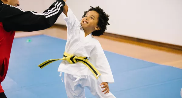 kid in karate uniform high fives