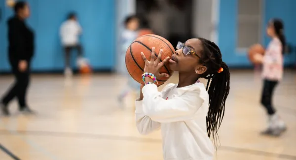 girl throws basketball in gym
