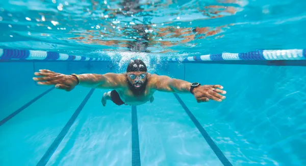 man swimming underwater in pool