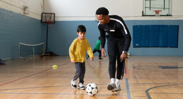 coach and kid with soccer ball in gym