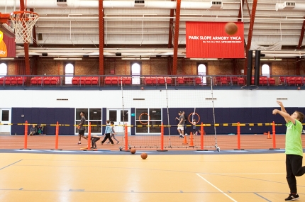 Family playing basketball at the Park Slope Armory YMCA indoor gymnasium