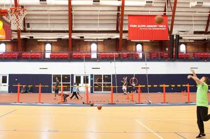 Family playing in gym together with basketball at YMCA