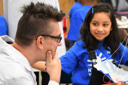A child at a Y camp shows a counselor her science project