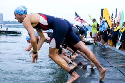 Swimmers dive into the water during the NYC triathlon.