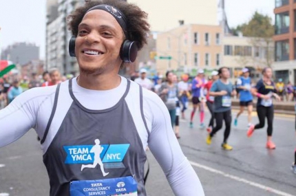 A marathon runner on Team YMCA high fives a passerby during the marathon.