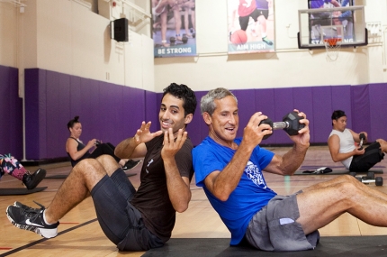 Two members work out with free weights in a class.