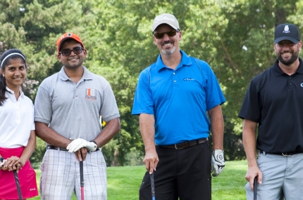 Four people in golf gear at a golf course.