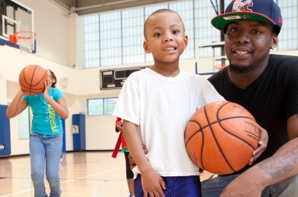 Family playing in gym together with basketball at YMCA