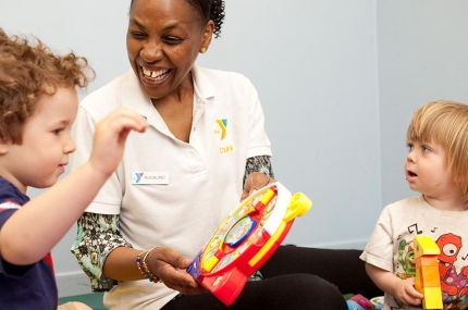 YMCA staff member with two toddler boys playing with toys during YMCA free child watch