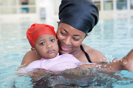 Mom and baby swim in YMCA indoor pool during mommy and me swimming class