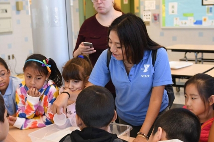 After school instructor helping children at YMCA program in Queens elementary school