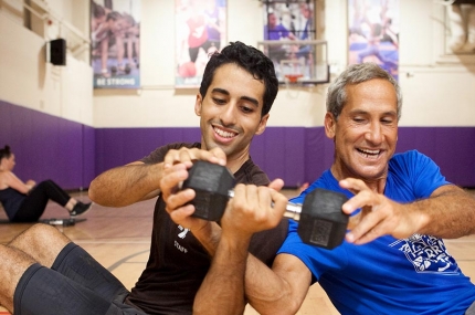 Two adult men passing weight to each other at YMCA gymnasium