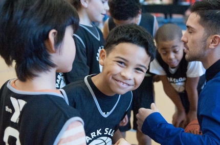 Boy smiling in group of basketball players at Park Slope Armory YMCA basketball league on indoor court