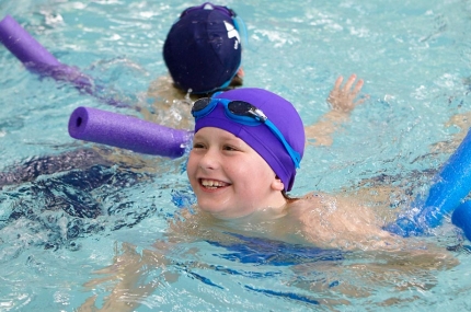 Kids swimming with noodles in YMCA indoor pool