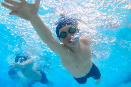 Boy swims laps at McBurney YMCA indoor pool with bubbles coming out of his face