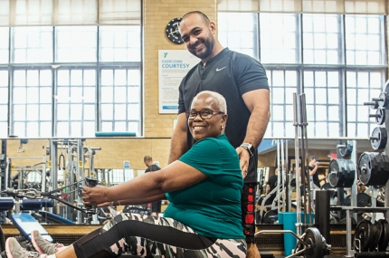 Woman working out in weight room of West Side YMCA with personal trainer