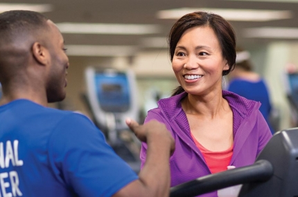 YUSA personal trainer talks to woman walking on treadmill