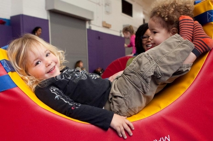 Toddlers playing on gym equipment in YMCA indoor gymnasium