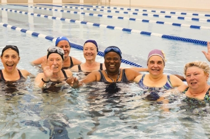 Group of women smiling at YMCA indoor pool water fitness class