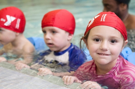 Group of preschoolers holding on to wall of indoor pool at Staten Island Broadway YMCA