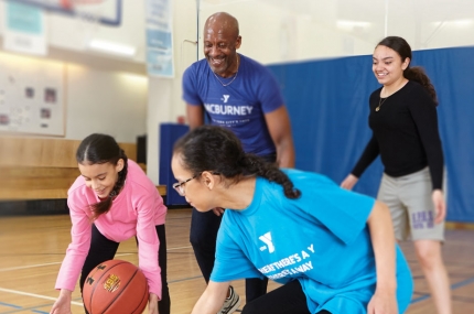Family playing in gym together with basketball at YMCA