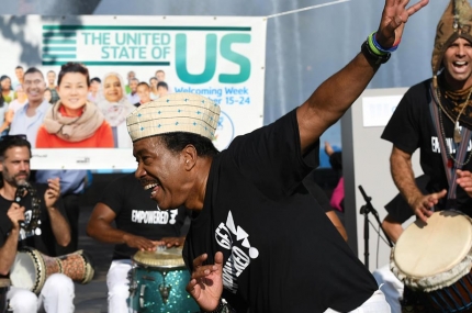 New Americans event at Flushing Meadows Corona Park with drums and dancing in front of globe