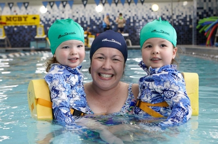 Mom holds two toddler daughters while swimming at McBurney YMCA indoor pool