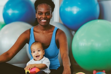 Mom sitting on yoga mat with baby and exercise balls