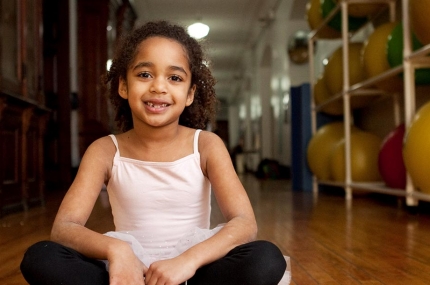 Girl sitting on floor of Park Slope Armory YMCA hallway in ballerina tutu