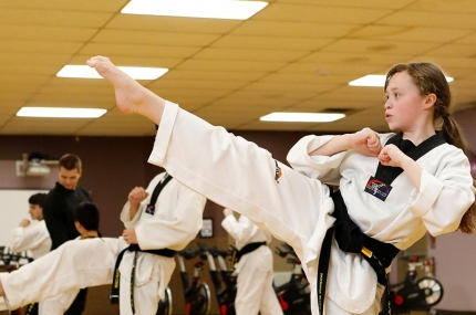Girl doing high karate kick in YMCA martial arts studio in Staten Island