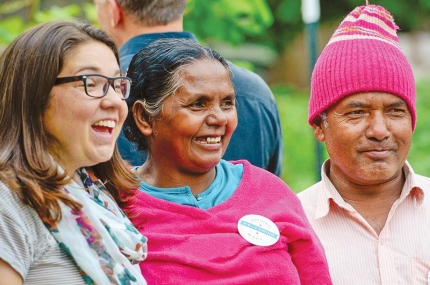 Two women and one man wearing a pink hat smile at something out of screen during YMCA event