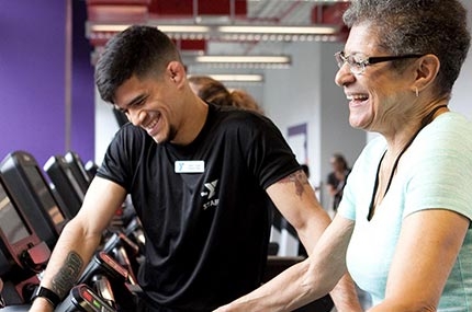 Personal trainer smiling while client walks on treadmill during training session