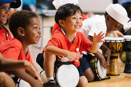 Boys smiling and playing drums at Bronx YMCA summer camp