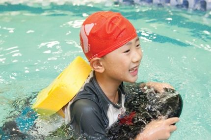 Boy with backpack and kickboard learns to swim at Vanderbilt YMCA summer camp