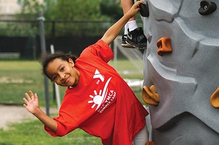 Summer camper climbing rock wall