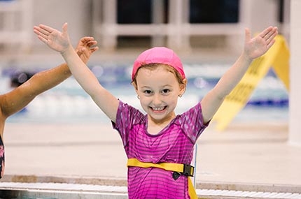 Girl with pink swim cap and arms in Y