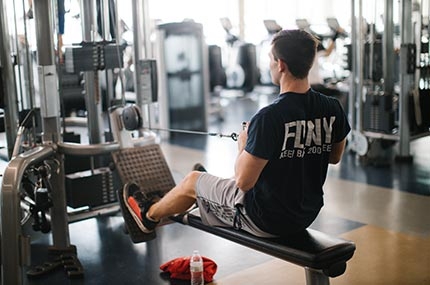 FDNY man using row weight machine at Rockaway YMCA in Queens
