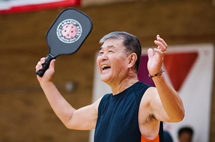 Man smiling with pickleball paddle