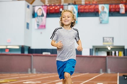 Boy running on track at Park Slope Armory YMCA kids run class in Brooklyn