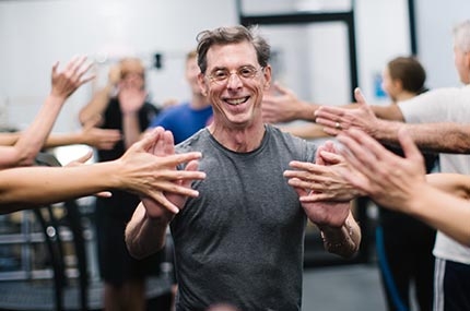 Man high fives classmates in YMCA fitness class