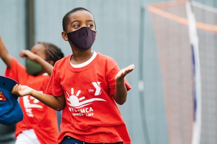 A boy in a mask running outside at YMCA Camp