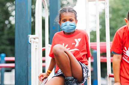 A girl in a mask playing outside at Y camp